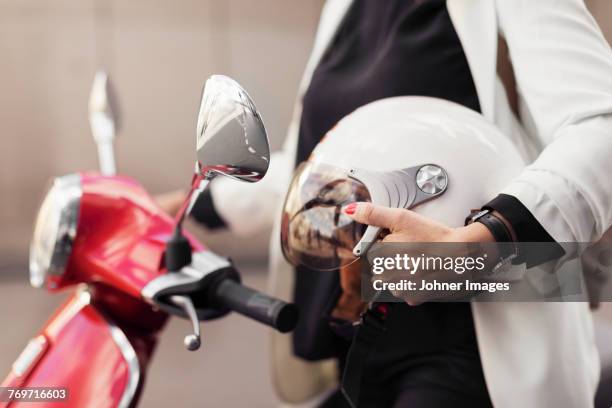 woman on scooter holding helmet - crash helmet stock pictures, royalty-free photos & images