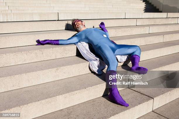 man dressed as superhero lying on steps - funny mask stock-fotos und bilder