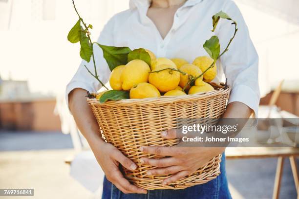 woman holding basket full of lemons - full frontal stock-fotos und bilder