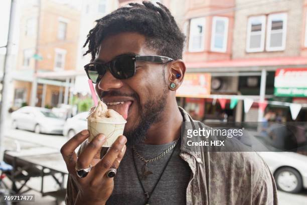 a young man eating frozen yogurt. - man tongue stock pictures, royalty-free photos & images