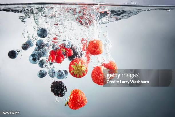 close-up of various berries in splashing water - slow motion water stock pictures, royalty-free photos & images