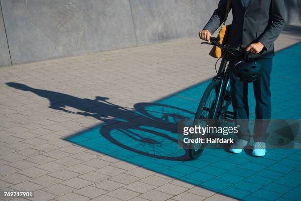 low section of businessman standing with bicycle on street - electric bike stockfoto's en -beelden