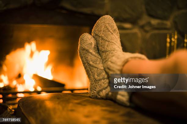 feet in wool socks near fireplace - brandhout stockfoto's en -beelden