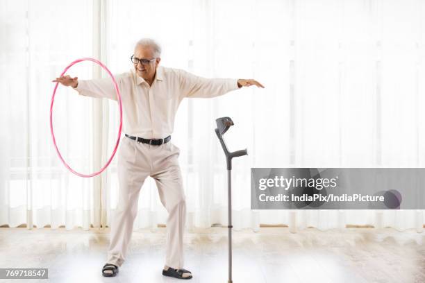 senior man exercising with hoopla hoop - gymnastikreifen stock-fotos und bilder