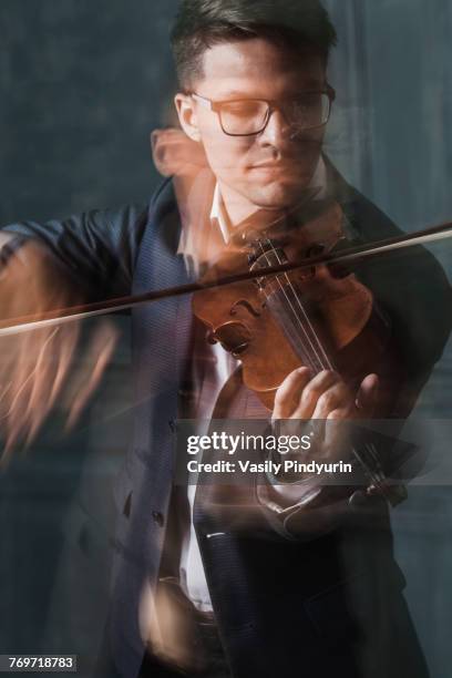 blurred motion of violinist playing violin against wall - tuning peg stock pictures, royalty-free photos & images