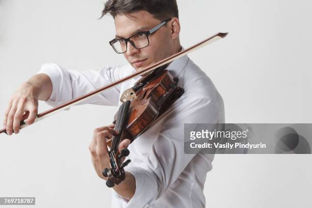 confident young man playing violin against white background - orchester stock-fotos und bilder