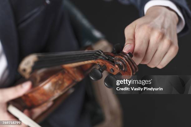 cropped image of musician tuning violin strings - stimmwirbel stock-fotos und bilder