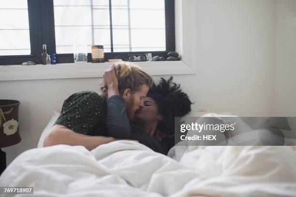 a young couple kissing in bed - black women kissing white men - fotografias e filmes do acervo