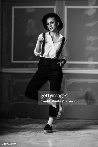 full length of young woman wearing suspenders standing against wall - women in suspenders stock pictures, royalty-free photos & images