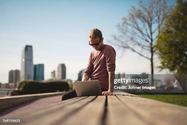 man using laptop in park - teleworking hipster stock pictures, royalty-free photos & images