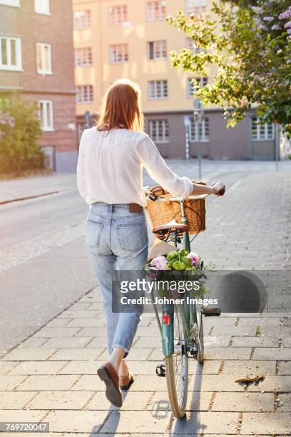 woman walking with bicycle - bike flowers stock-fotos und bilder