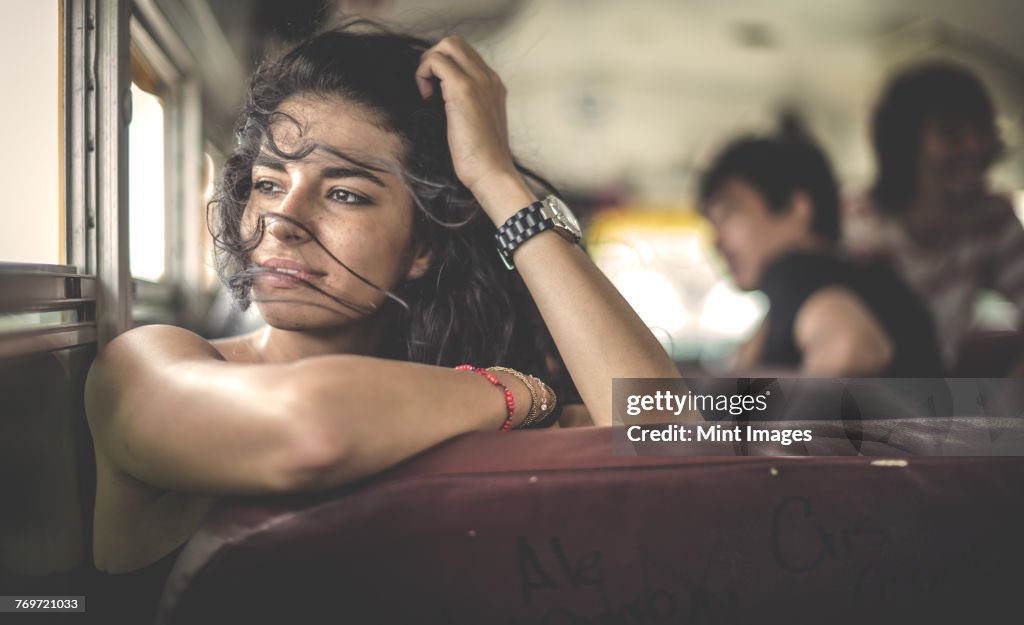 A young woman sitting on a school bus looking out of window.