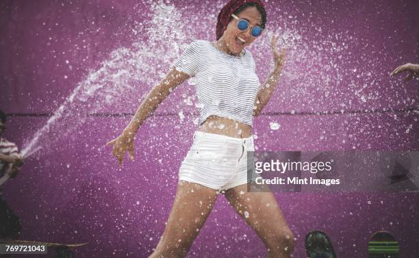 a young woman being sprayed with water. - water cooler stock-fotos und bilder