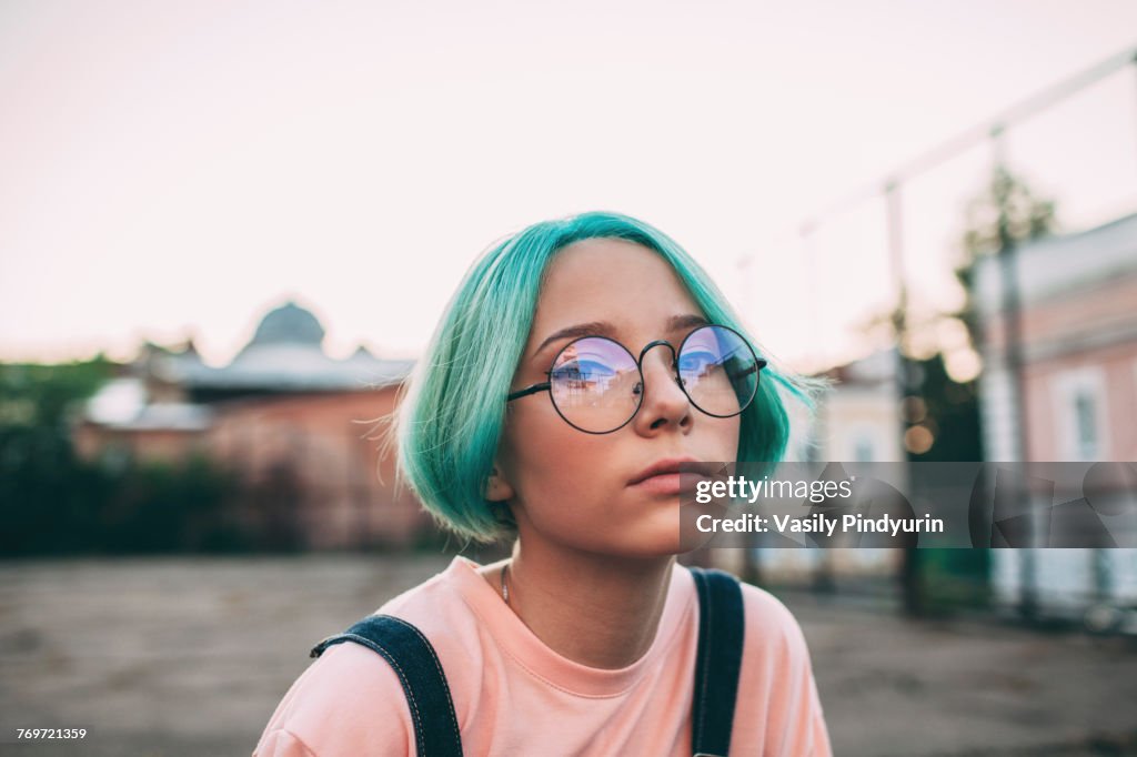 Portrait of teenage girl with green dyed hair wearing eyeglasses