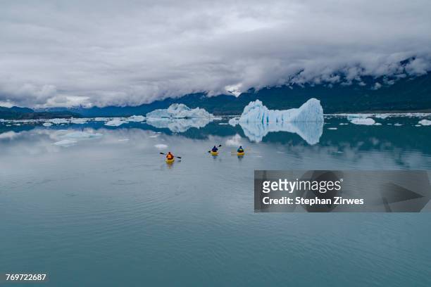 people canoeing in glacier lagoon against cloudy sky, knik glacier, palmer, alaska, usa - knik glacier stock pictures, royalty-free photos & images