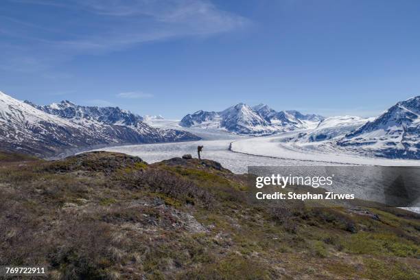 full length of hiker looking at glacier against blue sky, knik glacier, palmer, alaska - knik glacier stock pictures, royalty-free photos & images