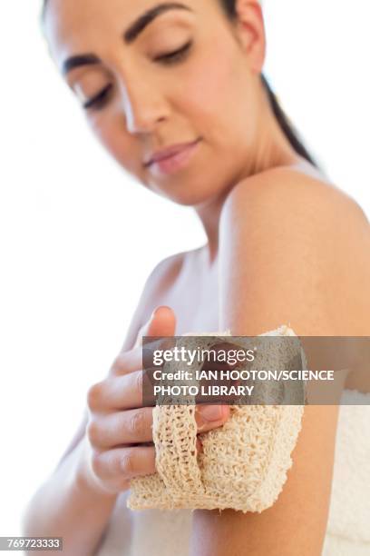woman using loofah mitt on arm - loofah fotografías e imágenes de stock