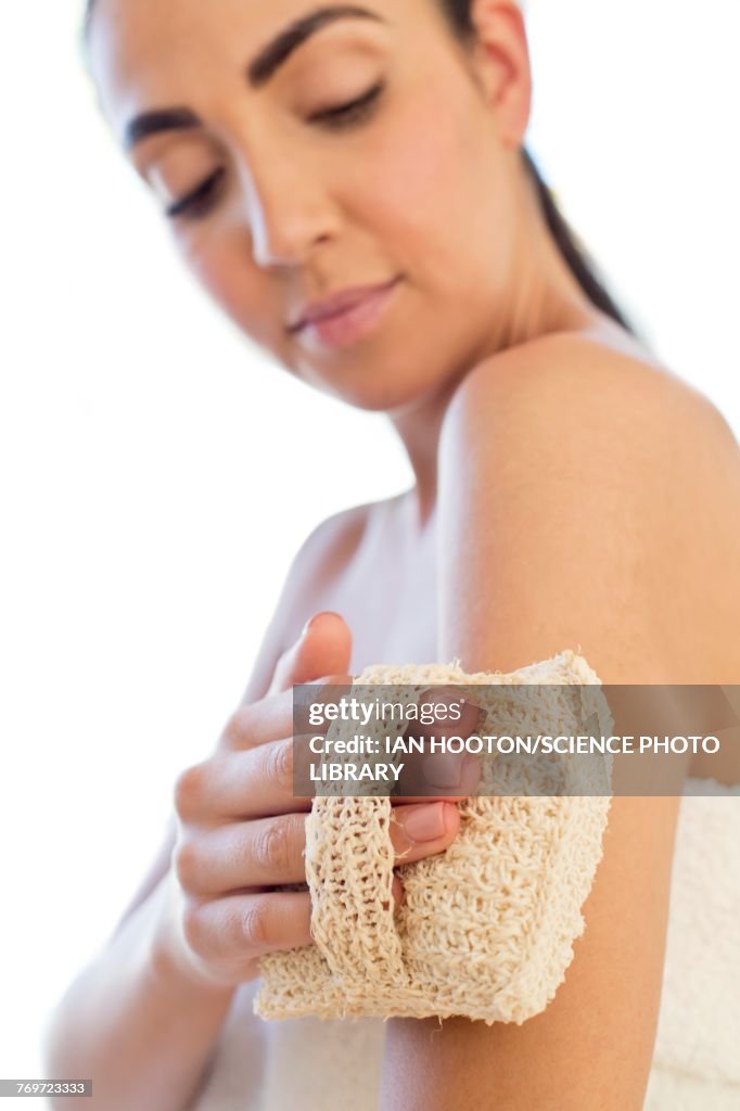 Woman using loofah mitt on arm