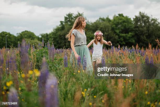 mother and daughter walking through meadow - solsticio de verano fotografías e imágenes de stock