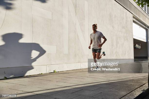young man running in the city - jogging photos et images de collection