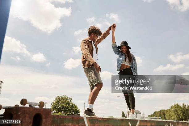 young couple standing on wall, raising arms - city wall ストックフォトと画像