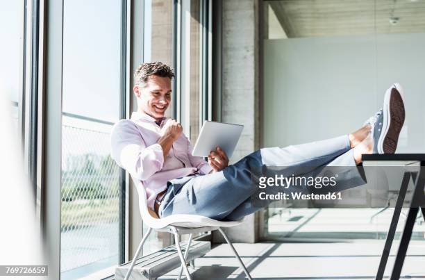 businessman sitting at desk with feet up, using digital tablet - feet up stock pictures, royalty-free photos & images