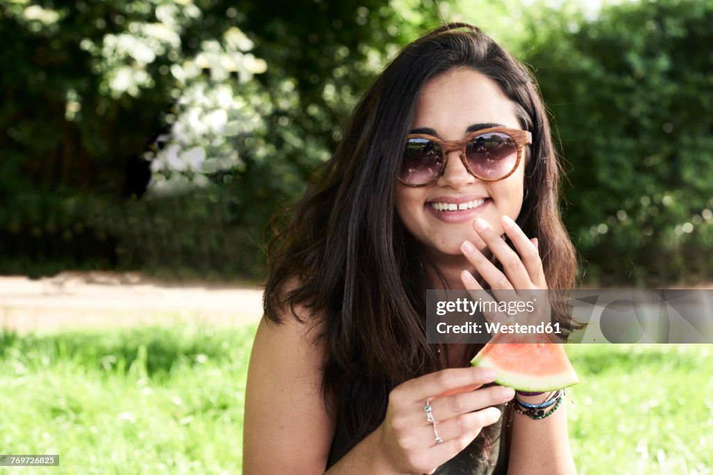 Young woman in park eating watermelon