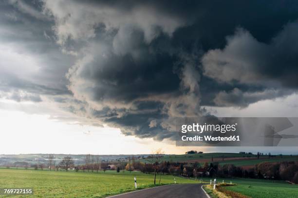 stormy atmosphere over empty country road - dark country road stock pictures, royalty-free photos & images