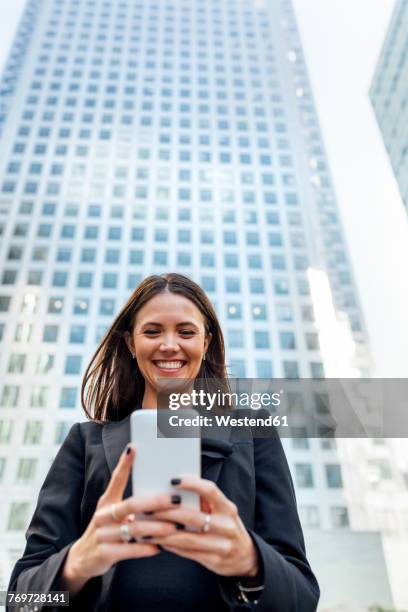 smiling woman looking at cell phone in the city - business forum in london stock-fotos und bilder