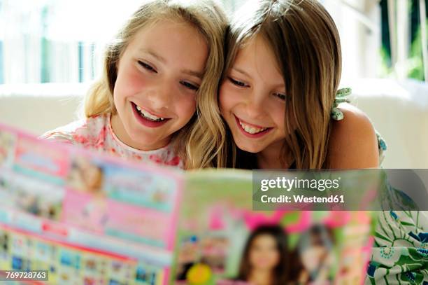 two girls reading teen magazine - only girls fotografías e imágenes de stock