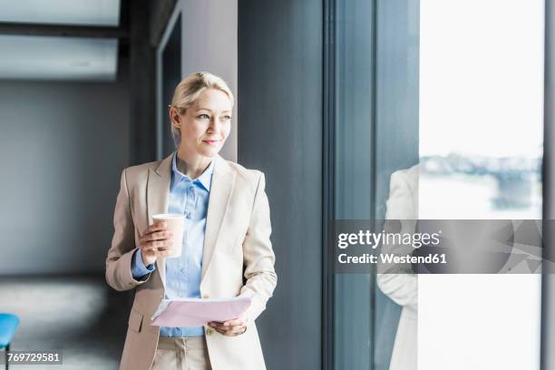businesswoman with coffee and documents at the window - woman in suit stock pictures, royalty-free photos & images