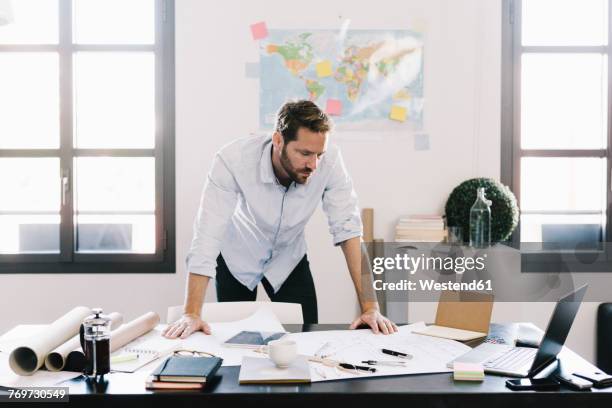 architect looking at construction plan in his office - bent over desk stock pictures, royalty-free photos & images