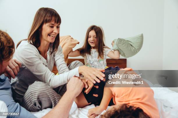 parents and their children having a pillow fight in bed - pillow fight stock pictures, royalty-free photos & images