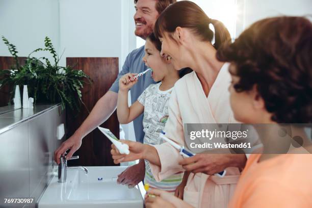 family of four brushing their teeth in bathroom - tooth bonding stock pictures, royalty-free photos & images