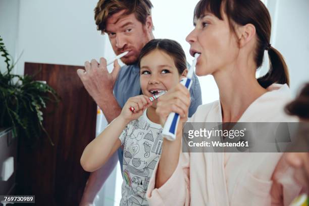 family of four brushing their teeth - elektrische zahnbürste stock-fotos und bilder