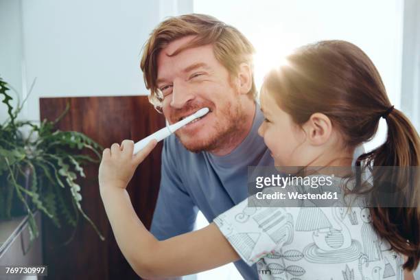 daughter brushing her father’s teeth in bathroom - dental bonding stock pictures, royalty-free photos & images
