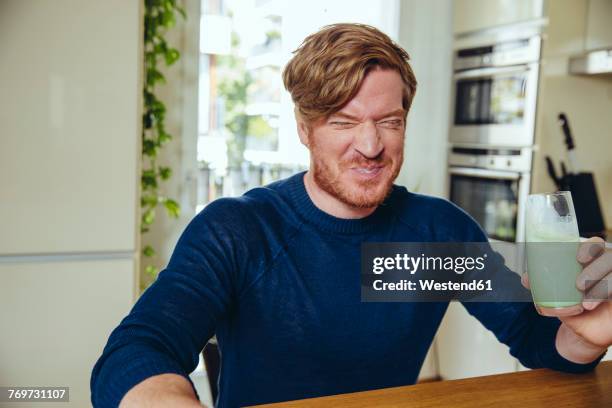 man making a funny face after drinking a healthy drink - disgust photos et images de collection