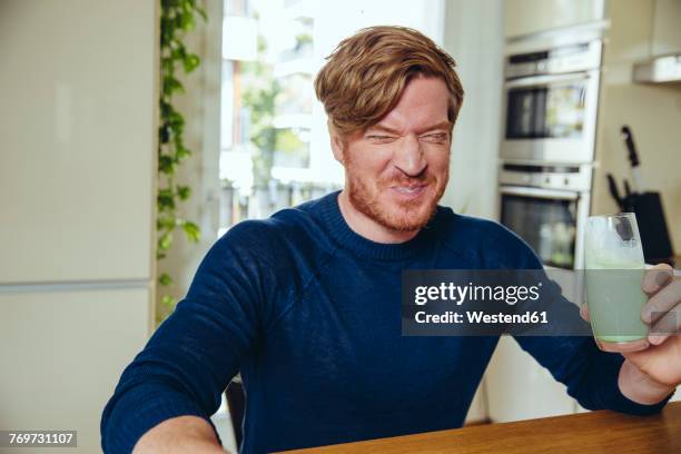 man making a funny face after drinking a healthy drink - funny face stockfoto's en -beelden