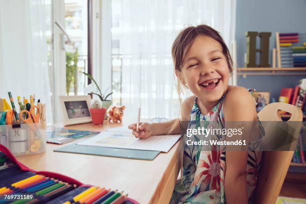 happy girl doing her schoolwork at home - young girls homework stockfoto's en -beelden