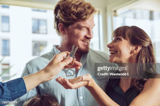 couple receiving key to their new home - house keys stock pictures, royalty-free photos & images