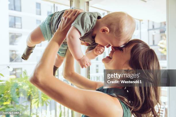 mother lifting up her baby at home - eltern baby hochheben stock-fotos und bilder