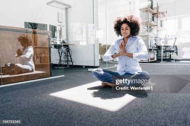 young woman doing yoga in office - employee wellbeing stock pictures, royalty-free photos & images