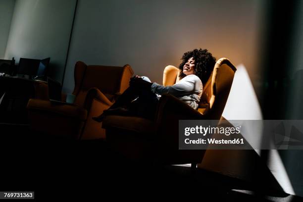 young woman having a break in office - lounge chair stock-fotos und bilder