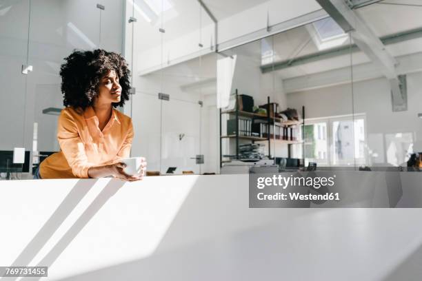 young woman having a coffee break in office - loft office stockfoto's en -beelden