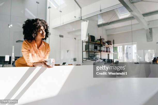 young woman having a coffee break in office - blusa cor de laranja imagens e fotografias de stock