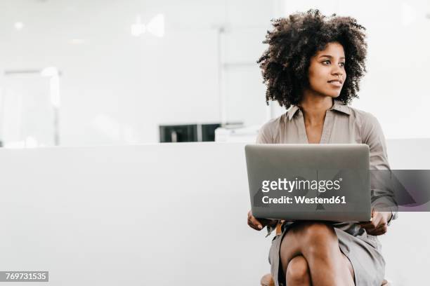young woman using laptop in office - sideways glance stock pictures, royalty-free photos & images