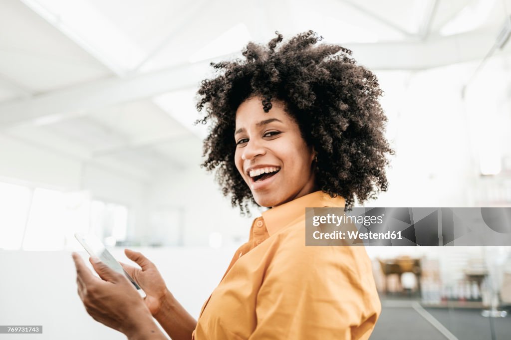 Portrait of happy young woman holding cell phone in office