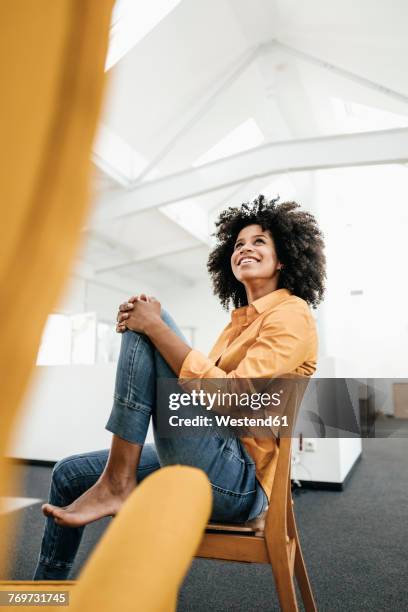 smiling young woman sitting on chair in office looking up - intérieur deco prendre la pose joie photos et images de collection