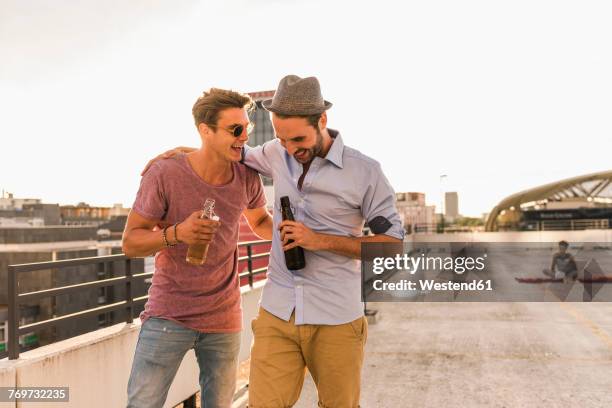 two friends with beer bottles on rooftop - drinking bier stock-fotos und bilder