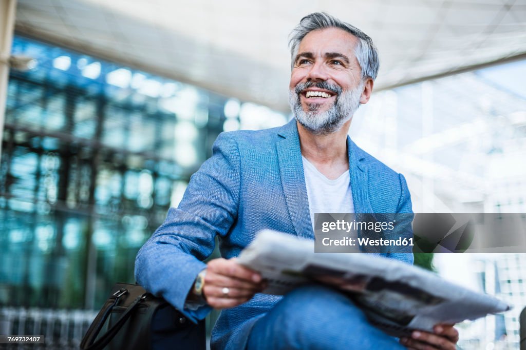 Happy businessman reading newspaper